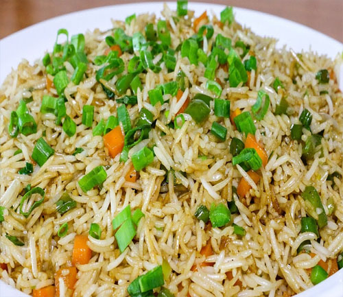 A colorful plate of rice with fresh vegetables and green onions, representing the best of Indian and Nepali cuisine.