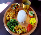 A serving of rice and vegetables on a plate with a cup of tea, representing the best of Indian and Nepali culinary offerings.