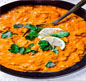 A delicious bowl of red curry accompanied by lemon wedges and parsley, representing the best of Indian and Nepali cuisine.